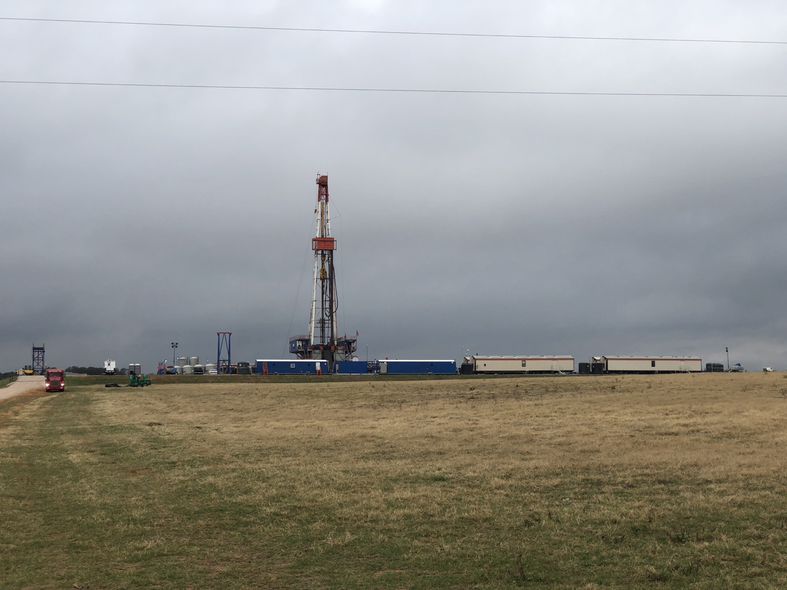 A drilling rig standing in a pasture under an overcast Texas sky