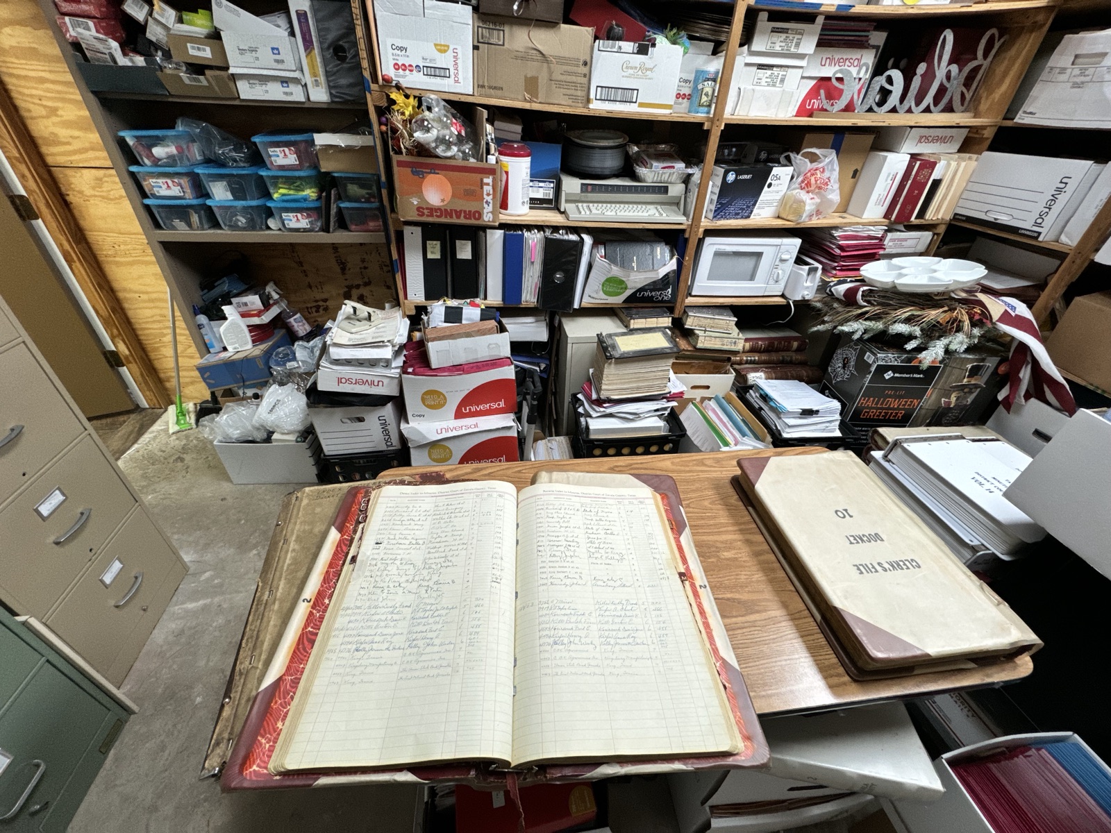 An open bound volume of county deed records on a table in a records room