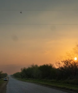 Shoes on a powerline outside Dilley Texas while the sun sets