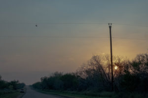 Shoes on a powerline outside Dilley Texas while the sun sets